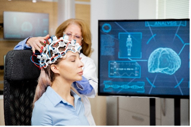 Woman with a biofeedback cap in front of a monitor.
